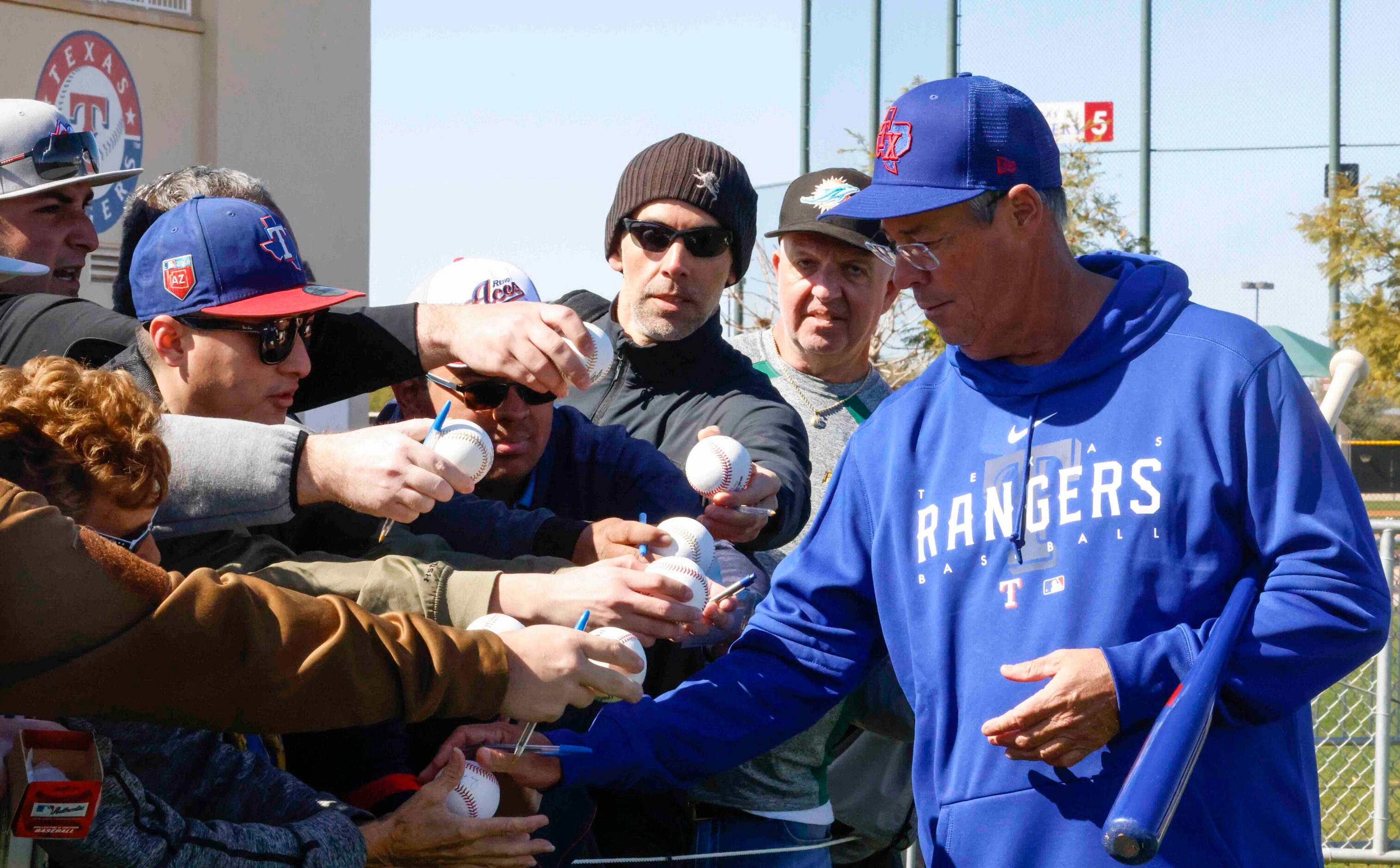 Texas Rangers special assistant Greg Maddux gives autographs to fans after the first spring...