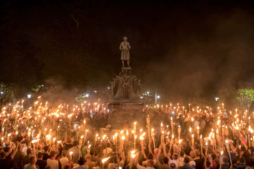 Torch-bearing white nationalists rally around a statue of Thomas Jefferson near the...