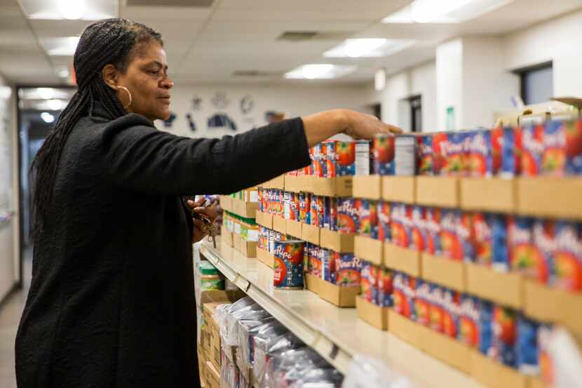 Program Director Candy Bradshaw organizes canned foods at the food pantry portion of Harmony...