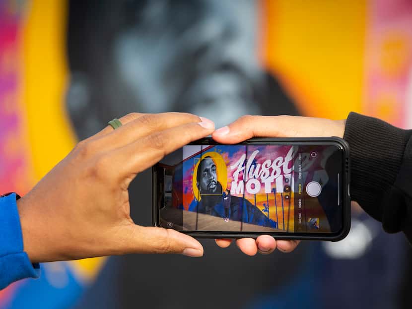 Dallas artist Jeremy Biggers helps take a photo for Oak Cliff residents Angel Ruiz and...