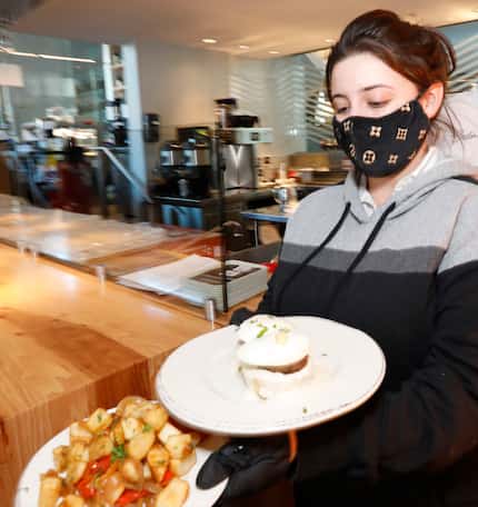 Server Kaitlyn Gonzales takes food to a customer's table at Overeasy in Dallas. The shop...