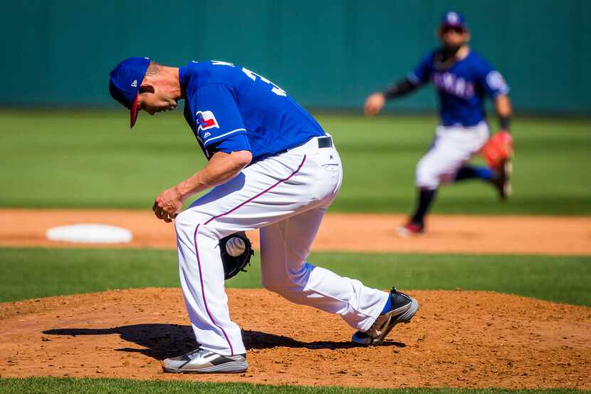 Texas Rangers pitcher Mike Minor fields a grounder off the bat of Seattle Mariners infielder...