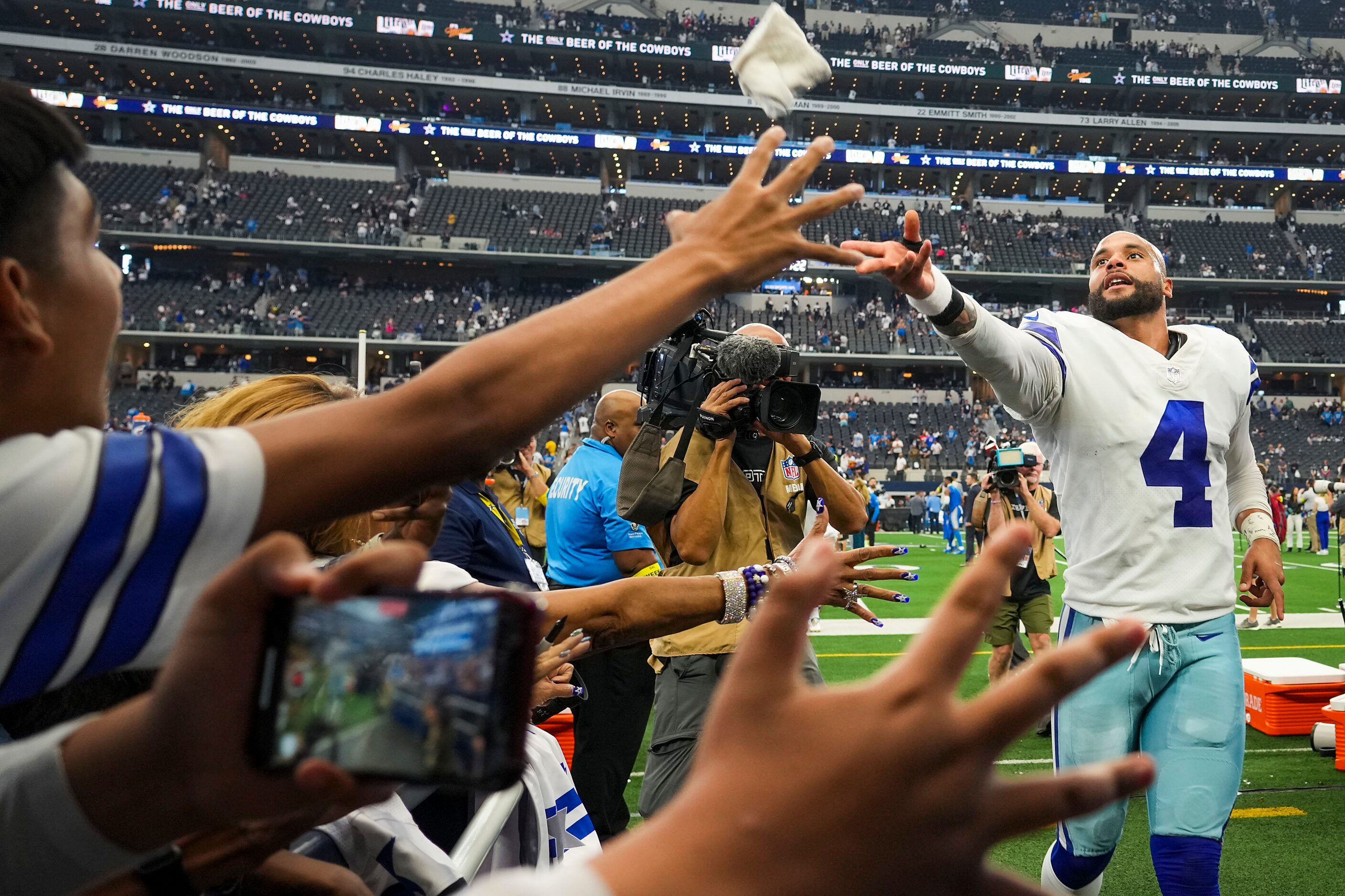 Dallas Cowboys quarterback Dak Prescott (4) tosses a wristband to the crowd as he leaves the...