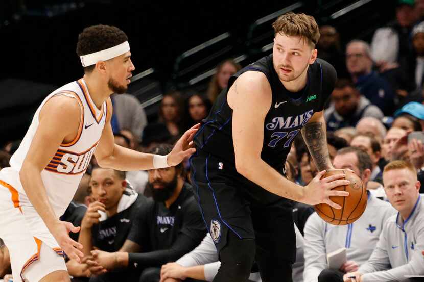 Dallas Mavericks guard Luka Doncic (77) keeps the ball away from Phoenix Suns guard Devin...