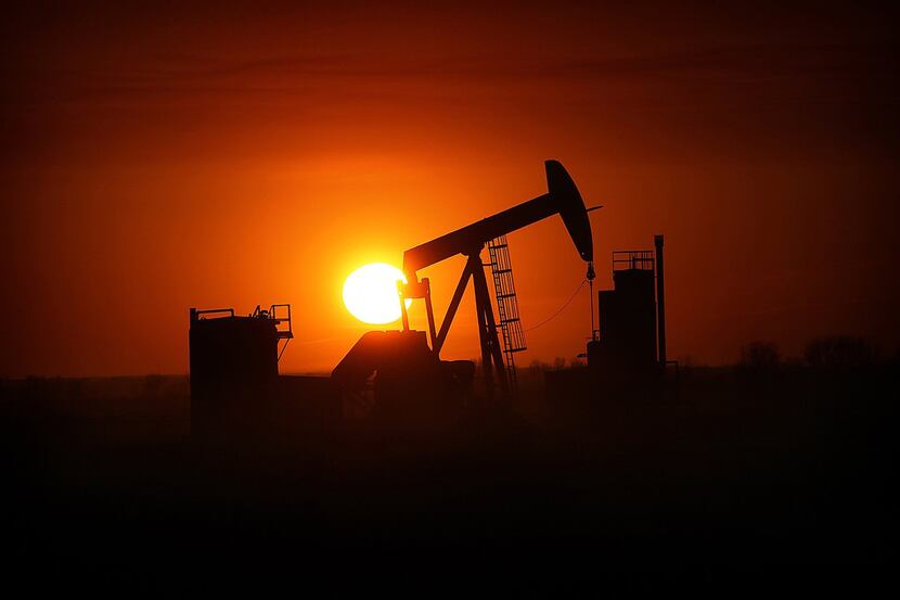 The sun sets over the Bakken Oil Formation, behind an oil well near Williston, N.D. 