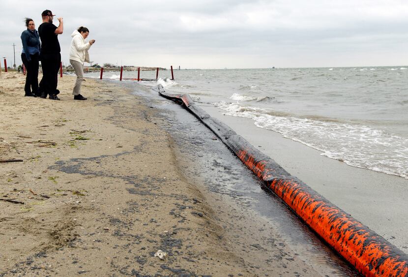 People photographed oil washing ashore Sunday along Boddeker Road in Galveston.