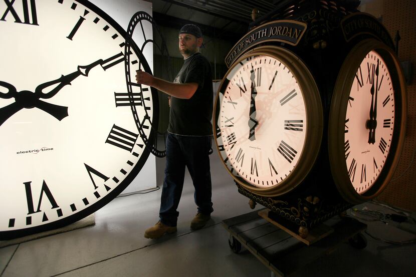 Dan LaMoore of Electric Time Co. moves a clock face at his plant in Medfield, Mass., between...