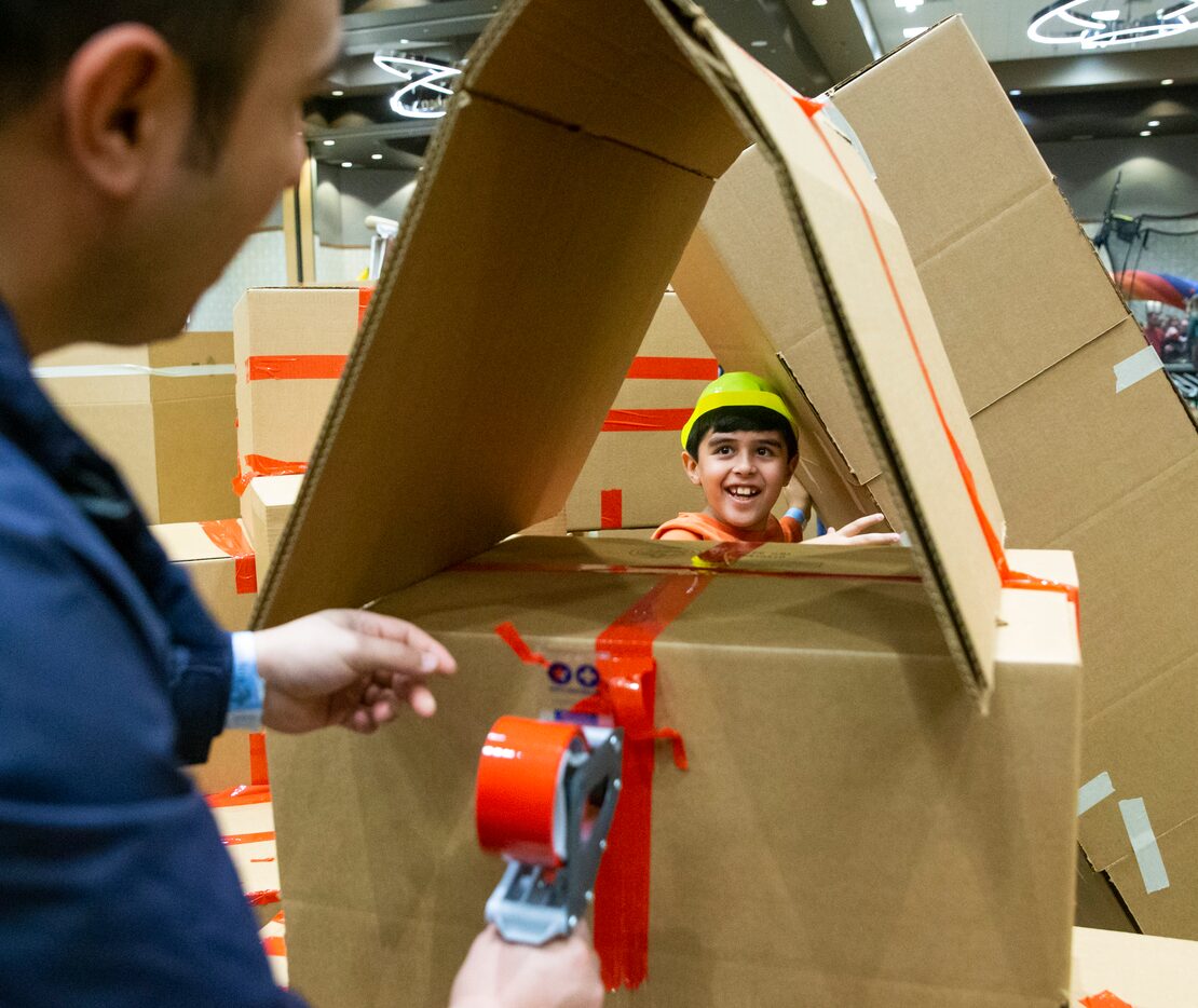 Sepehr Solhmirzei (center), 9, from Plano, Texas, looks at his dad, Mohammed, as they build...