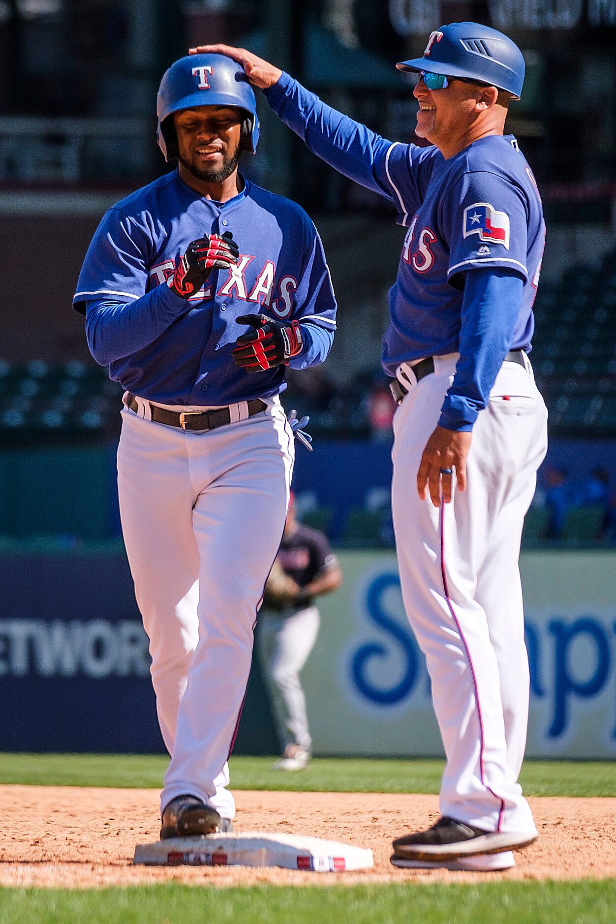 Texas Rangers outfielder Franklin Rollin celebrates with first base coach Hector Ortiz after...