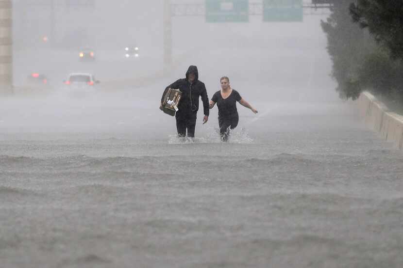 Two people walk down a section of Interstate 610 flooded by rain from Tropical Storm Harvey...