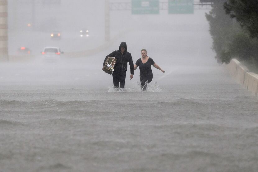 Two people walk down a flooded section of Interstate 610 in Houston on Sunday as Tropical...