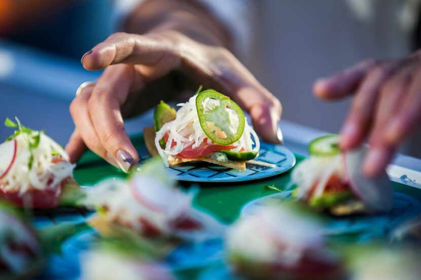 A woman reaches for a tuna tostada from Earl's Kitchen + Bar at Taste of the Cowboys on...