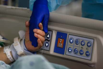 A 73-year-old woman holds a nurse’s hand while coming off sedatives before the removal of...