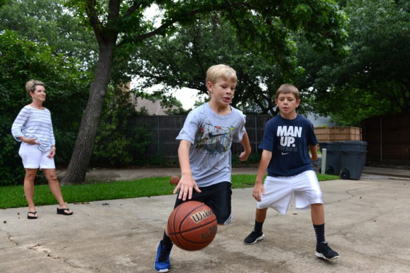 Janelle Rawlston (back left) watches her sons Matt, 10, (left) and Jack, 12, play basketball...