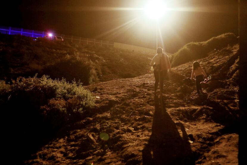 Honduran migrants walk on the U.S. side of the U.S.-Mexico border fence after crossing the...