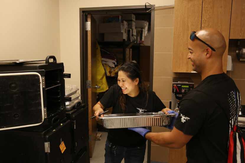 Jennifer Do takes a tray of food from Houston police Officer Mike Enriquez in the kitchen at...