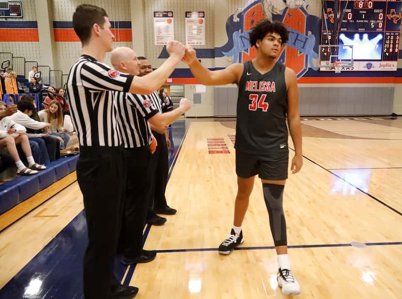 Melissa High School post Trevor Goosby (34) fist bumps the referees before tip-off as...