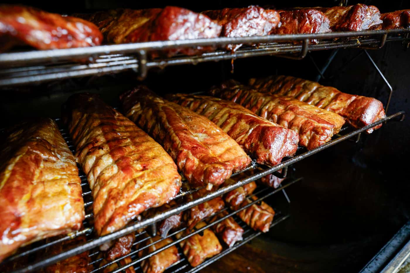 Racks of ribs rotate on the rotisserie smoker at Ribbee’s in Fort Worth. Barbecue fans,...