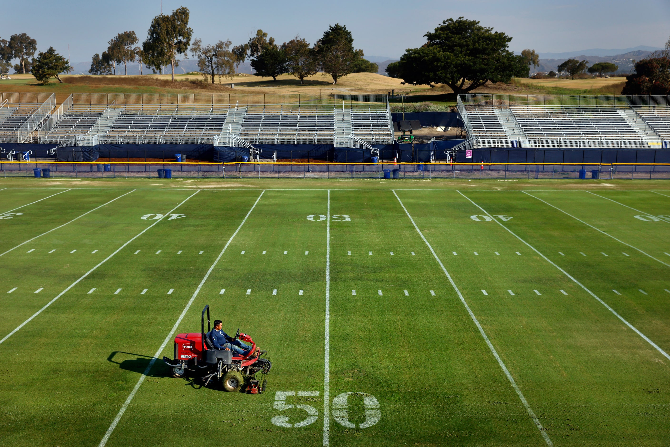 Grounds crewman Alberto Ortega cuts the grass fields in preparation for the Dallas Cowboys...