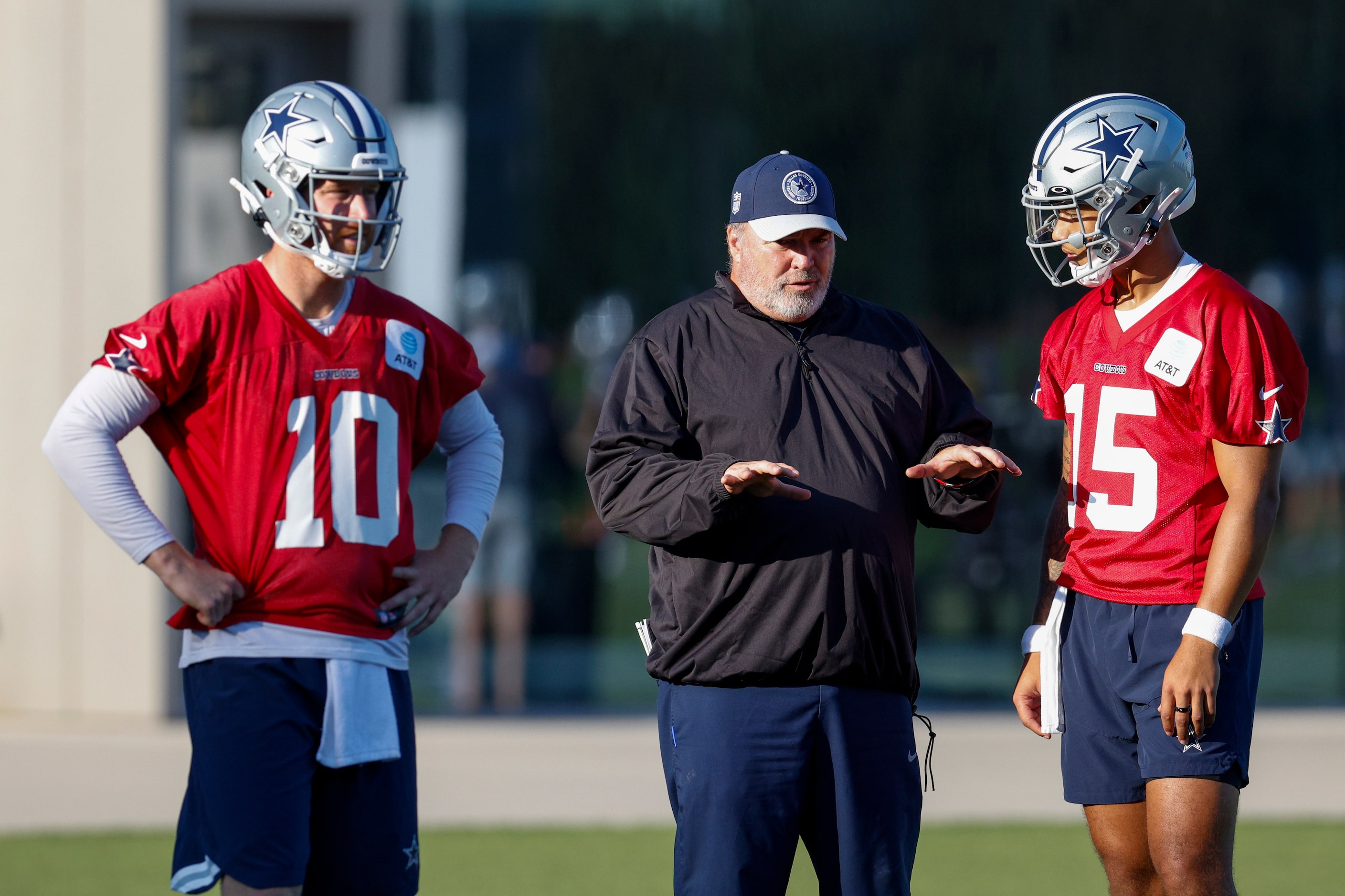 Dallas Cowboys head coach Mike McCarthy (center) talks with quarterbacks Trey Lance (15) and...