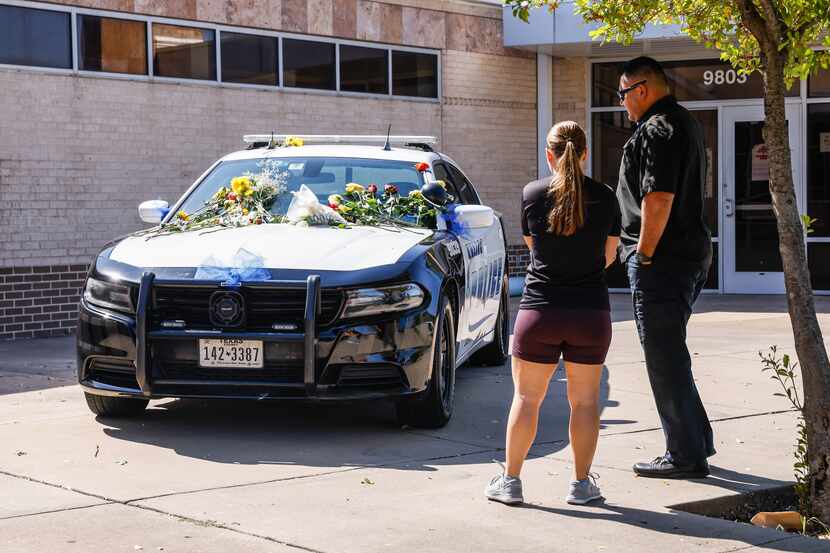 A Dallas police car is parked outside the northwest patrol division office  as a memorial...