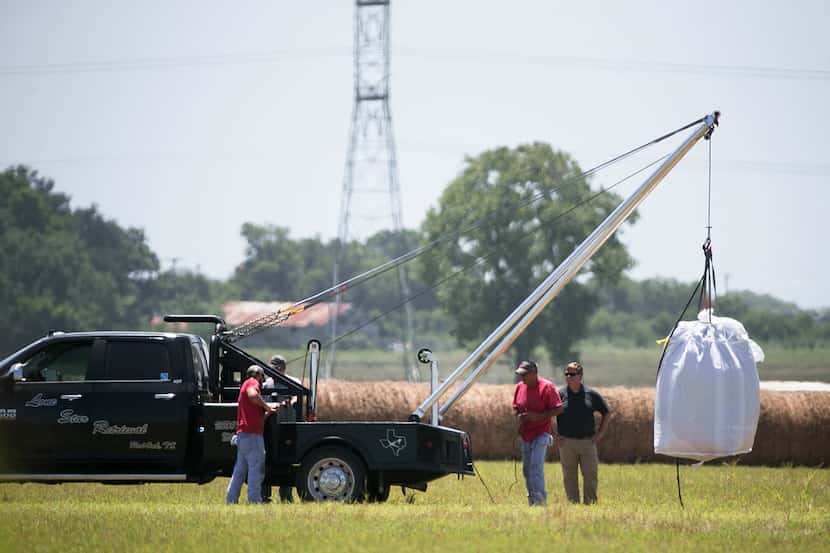 A crew hoists a bag holding the remains of a hot air balloon that crashed in 2016 onto a...
