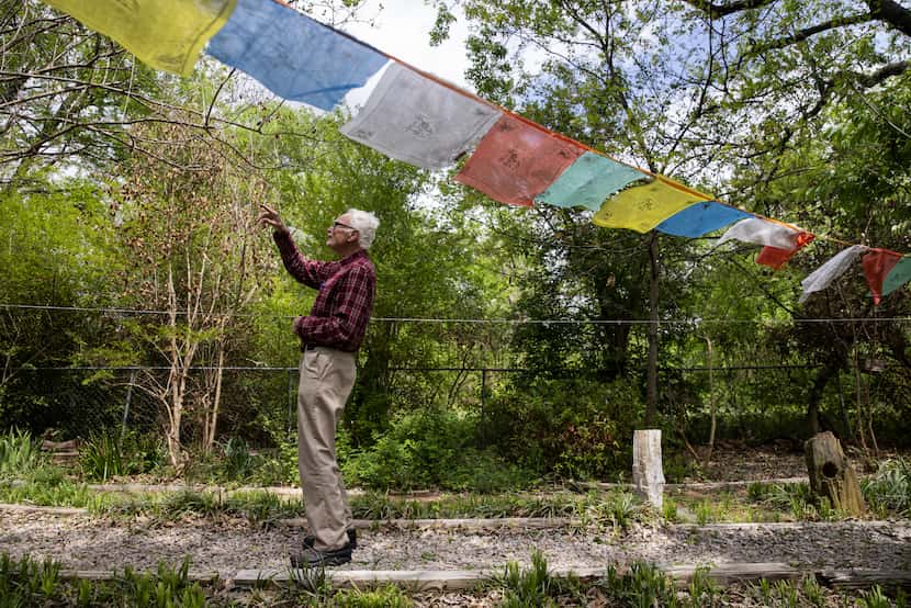The Rev. Timothy Gollob walks past a line of prayer flags in the backyard of his Oak Cliff...