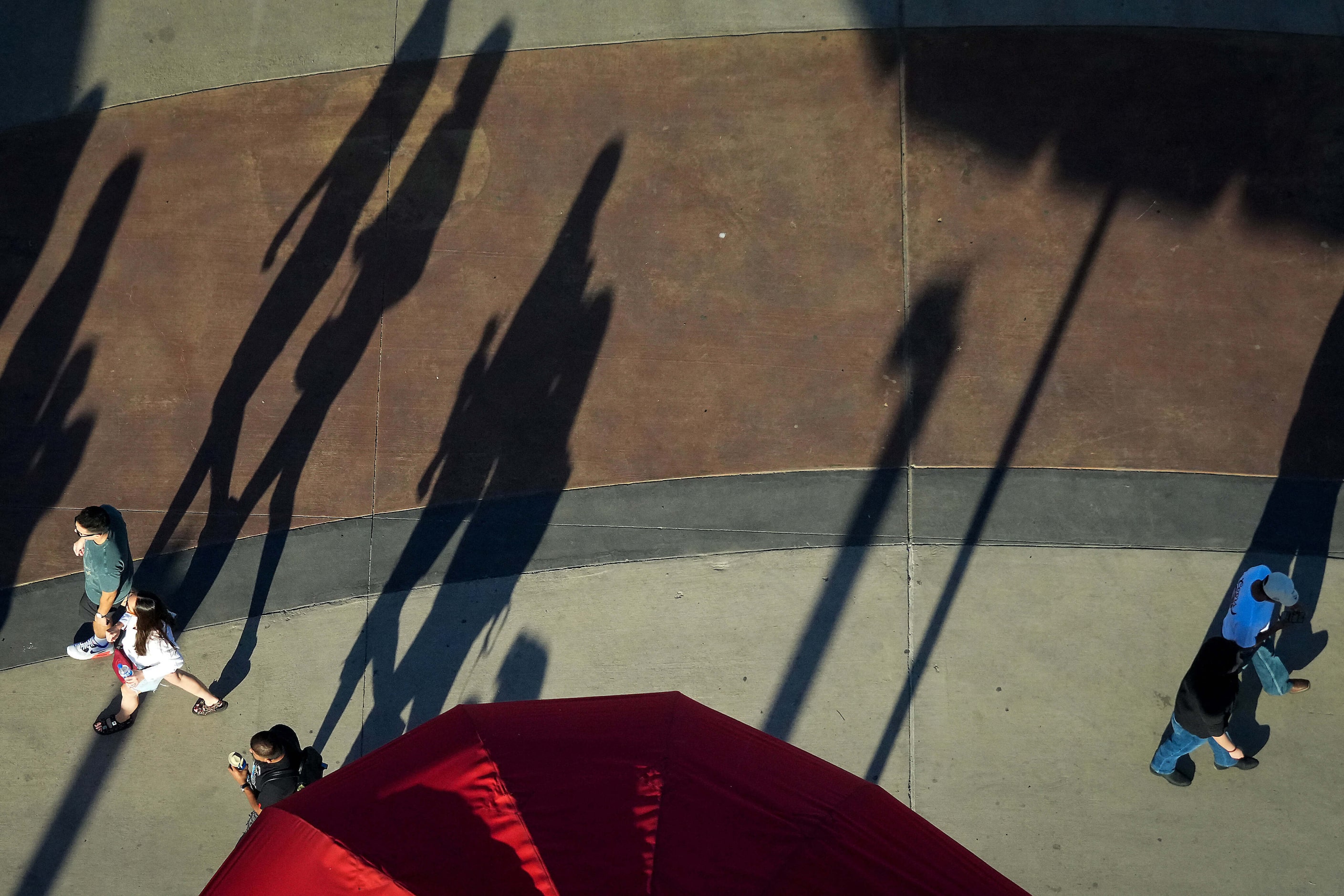 Fairgoers long shadow across the midway at the State Fair of Texas on Sunday, Sept. 29,...