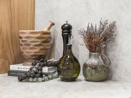 Bottles and cases, books and beads on a kitchen counter.