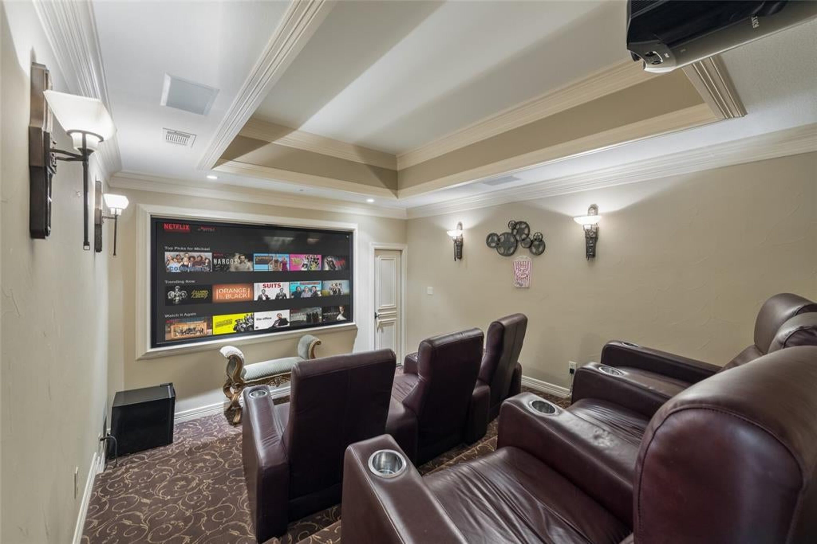 A small home theater has tiered seating in leather recliners.