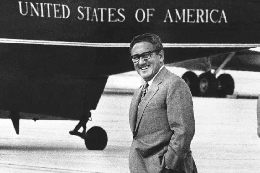 Henry Kissinger smiles as he walks to a helicopter at Andrews Air Force Base near...