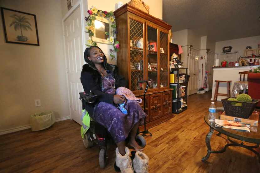 Mythia Joseph puts on warmer shoes as she sits in her motorized wheelchair, getting ready to...