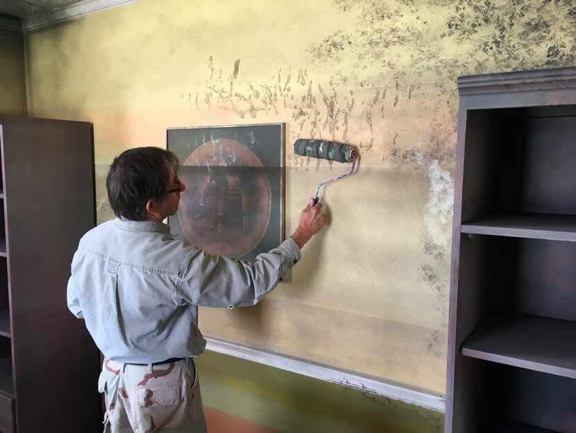Artist Ken Conner paints mold on the walls of the Flooded House Museum in New Orleans. 