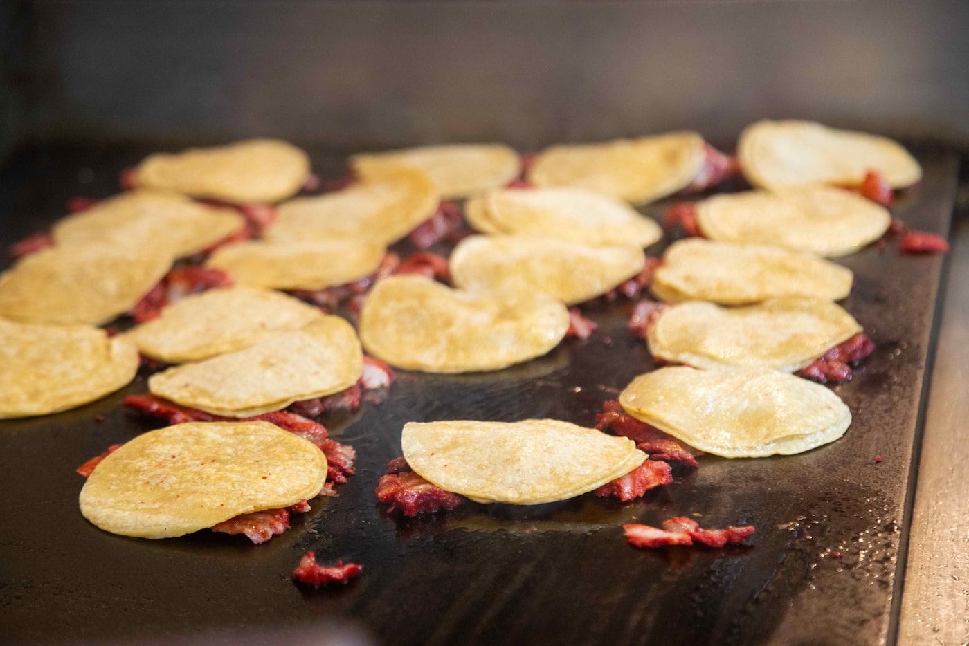 Tacos made from trompo cook on the grill at Taco Rey (Polkmart), a popular taco shop inside...