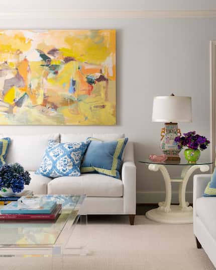 Living space with tan couch, bright yellow artwork and patterned blue pillows