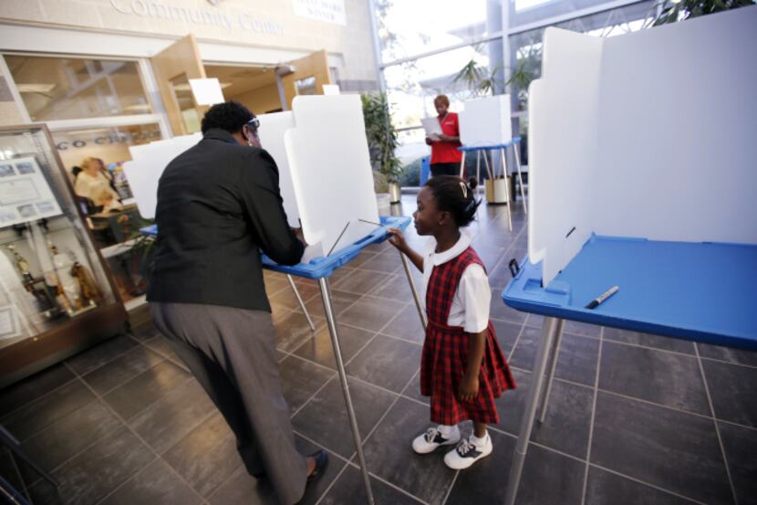 Christiana Adesanya, 6, watched her mother, Christine Adesanya of Irving, vote in November....