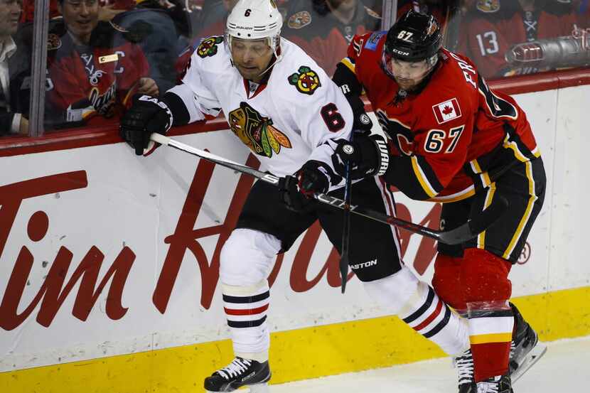 Chicago Blackhawks' Trevor Daley, left, is checked by Calgary Flames' Michael Frolik, from...