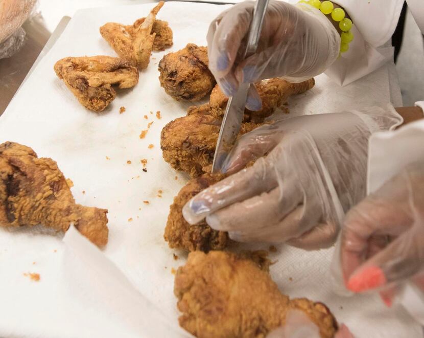 Lincoln High School  culinary student Kameran Thomas cuts into a piece of fried chicken to...