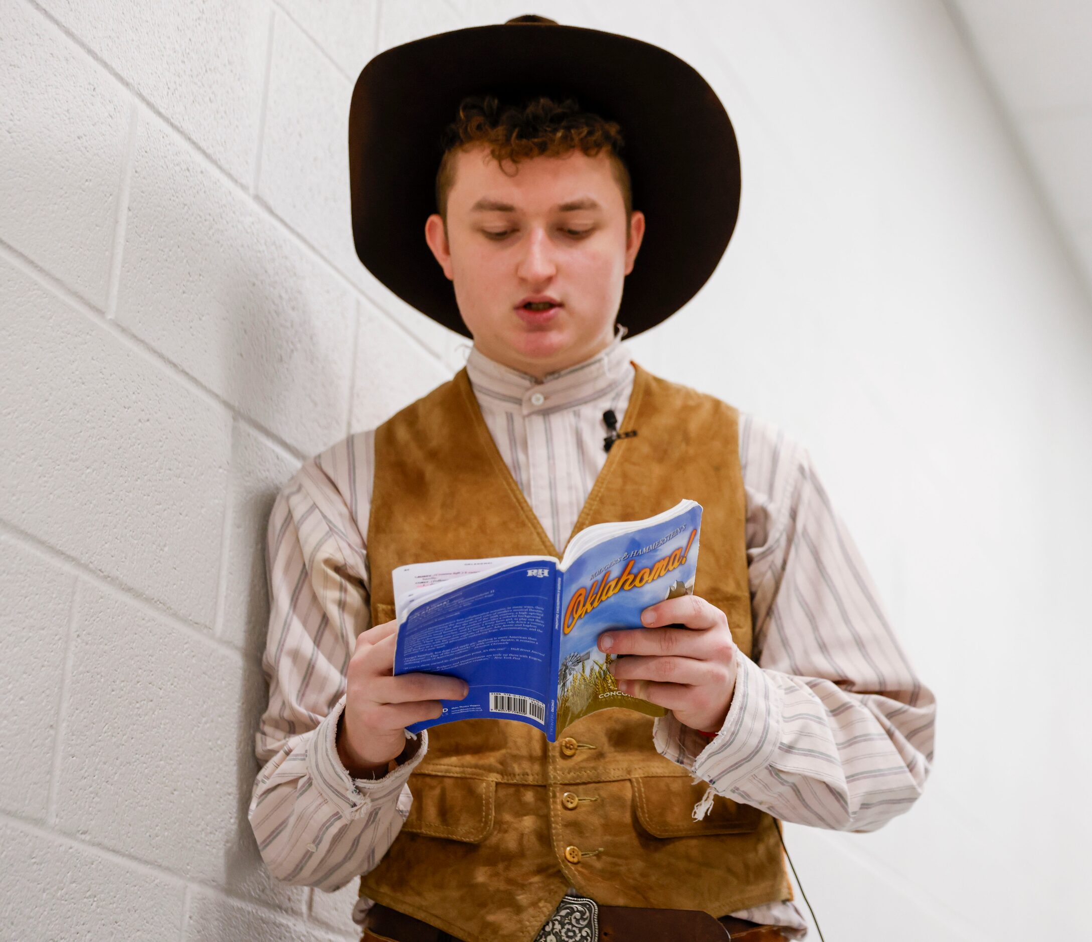 Cast member Tucker White playing as Curly, reads the lines of Oklahoma! behind the stage...