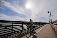 A cyclist rides across a bridge at White Rock Lake, Monday, Feb. 26, 2024, in Dallas.