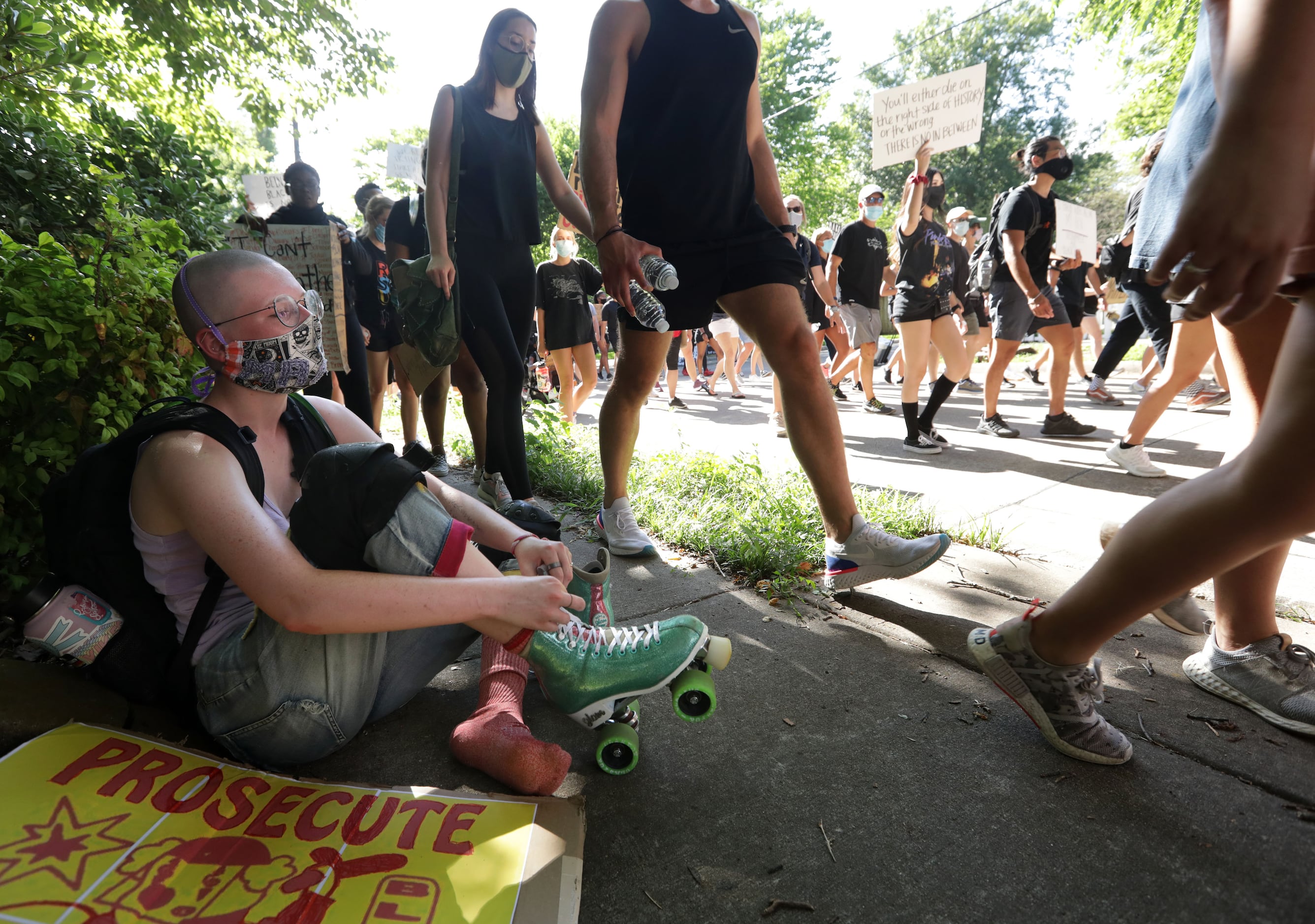 Helen Carter Flanagan, right, adjusts her rollerskates as protestors march down the streets...
