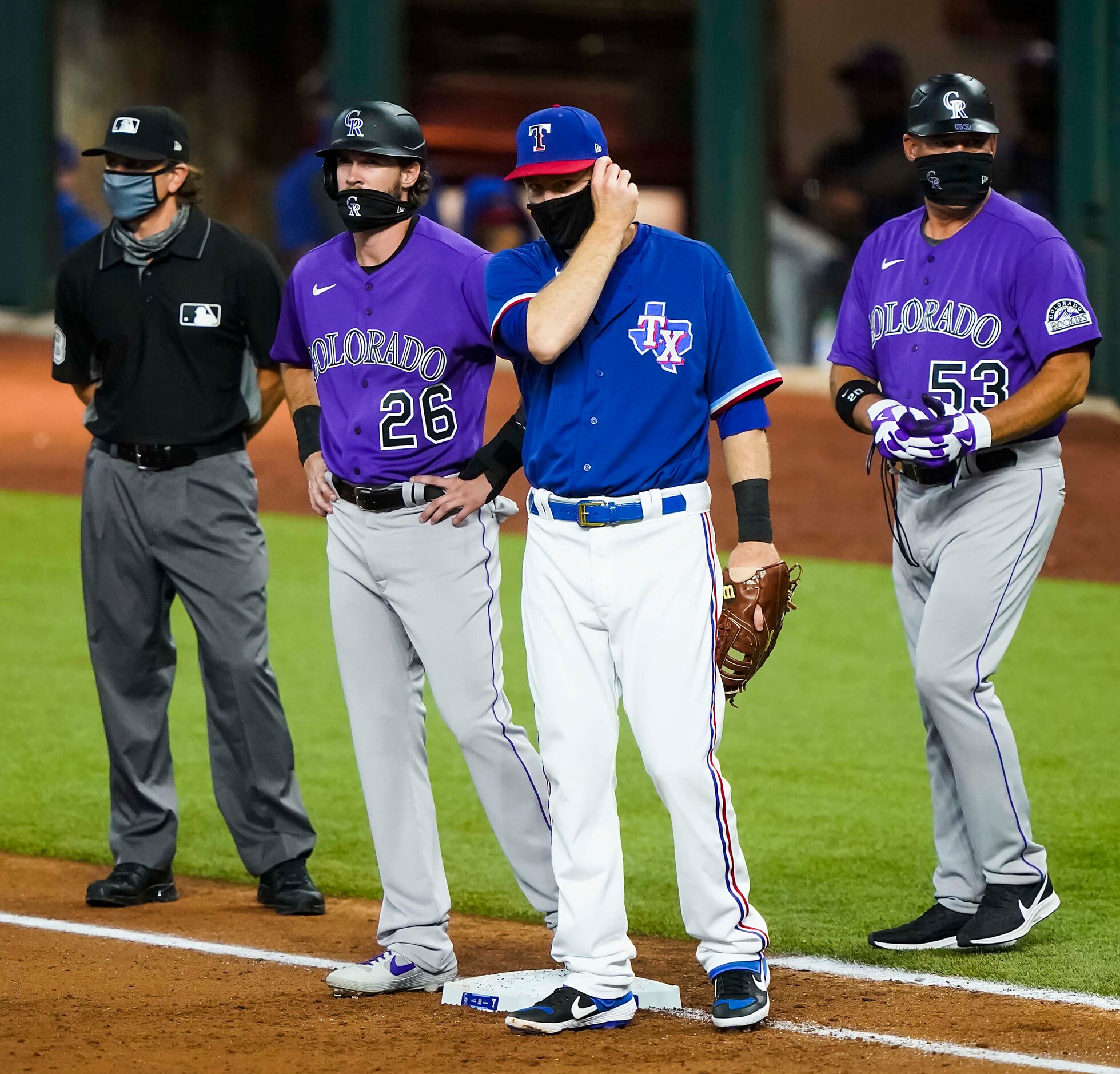 Texas Rangers first baseman Todd Frazier adjusts his face mask as umpire Chris Guccione,...