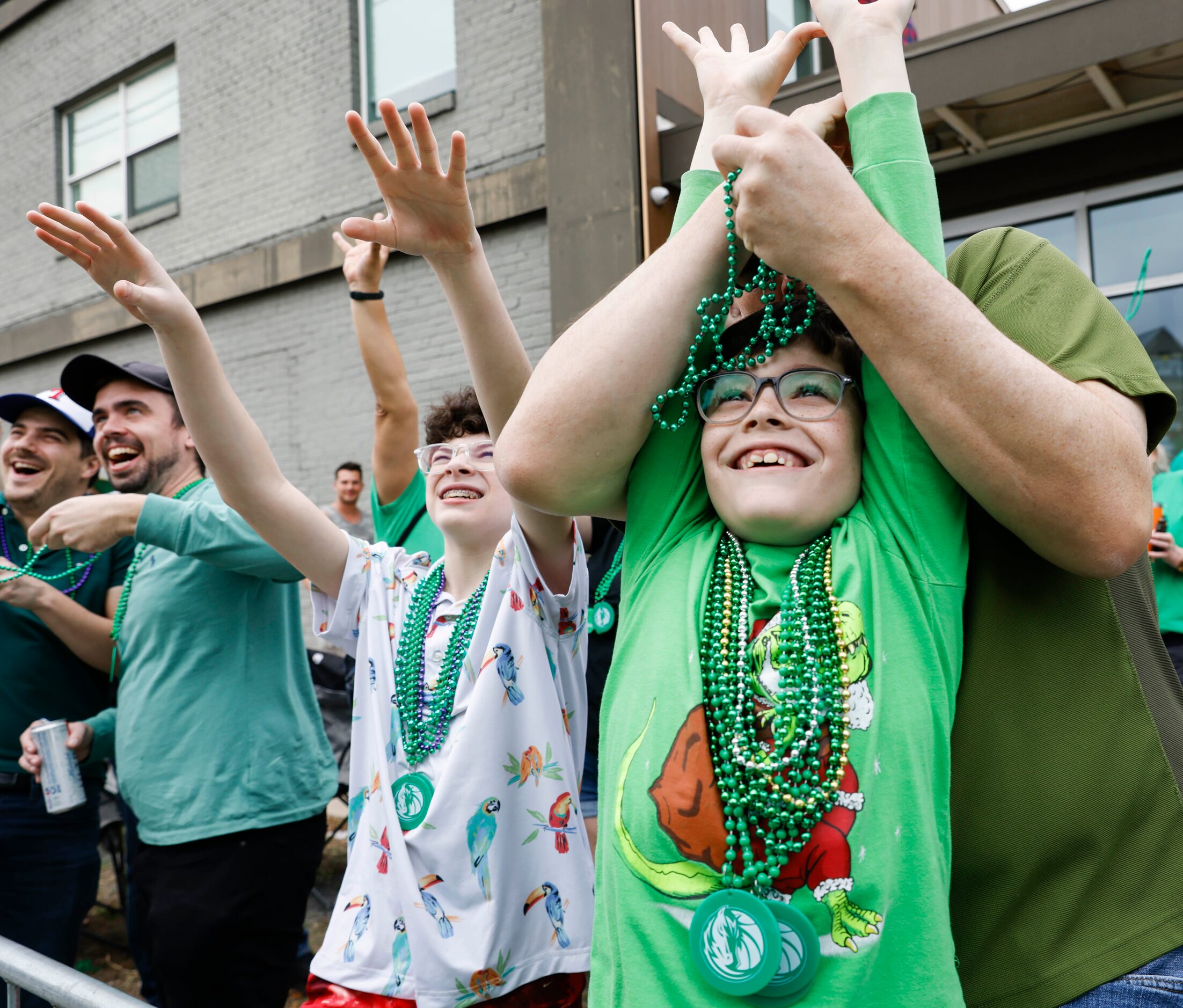 Attending crowd tries to catch green bead necklaces tossed by marchers during a Saint...