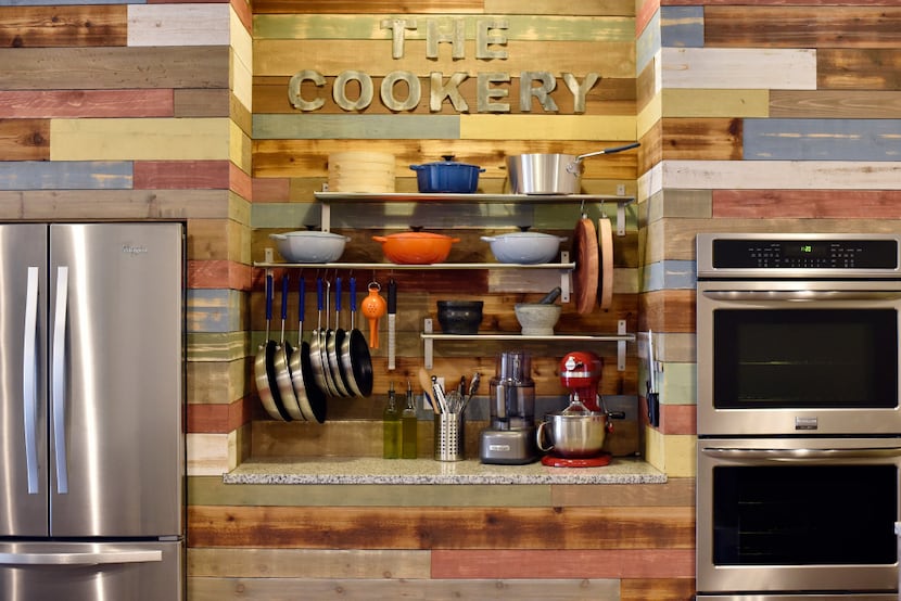 Cookware is stored on a countertop between the refrigerator and oven at The Cookery.