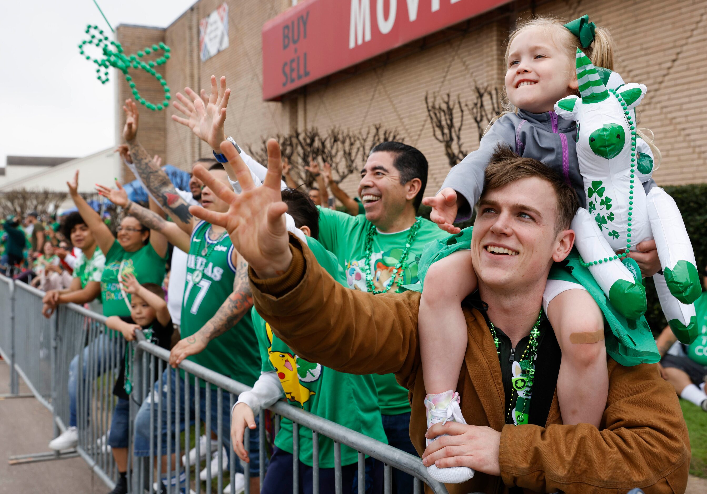 Mason Wright carrying his daughter Eden, 4, catches a green bead necklaces tossed by...