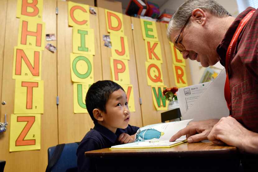 Volunteer Eric Samuelsen works with first-grader Rain Nawn on his reading skills with a Dr....