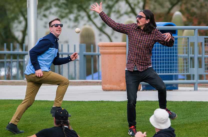 Fans in the grass behind the right field wall at Peoria Sports Complex try to catch a home...