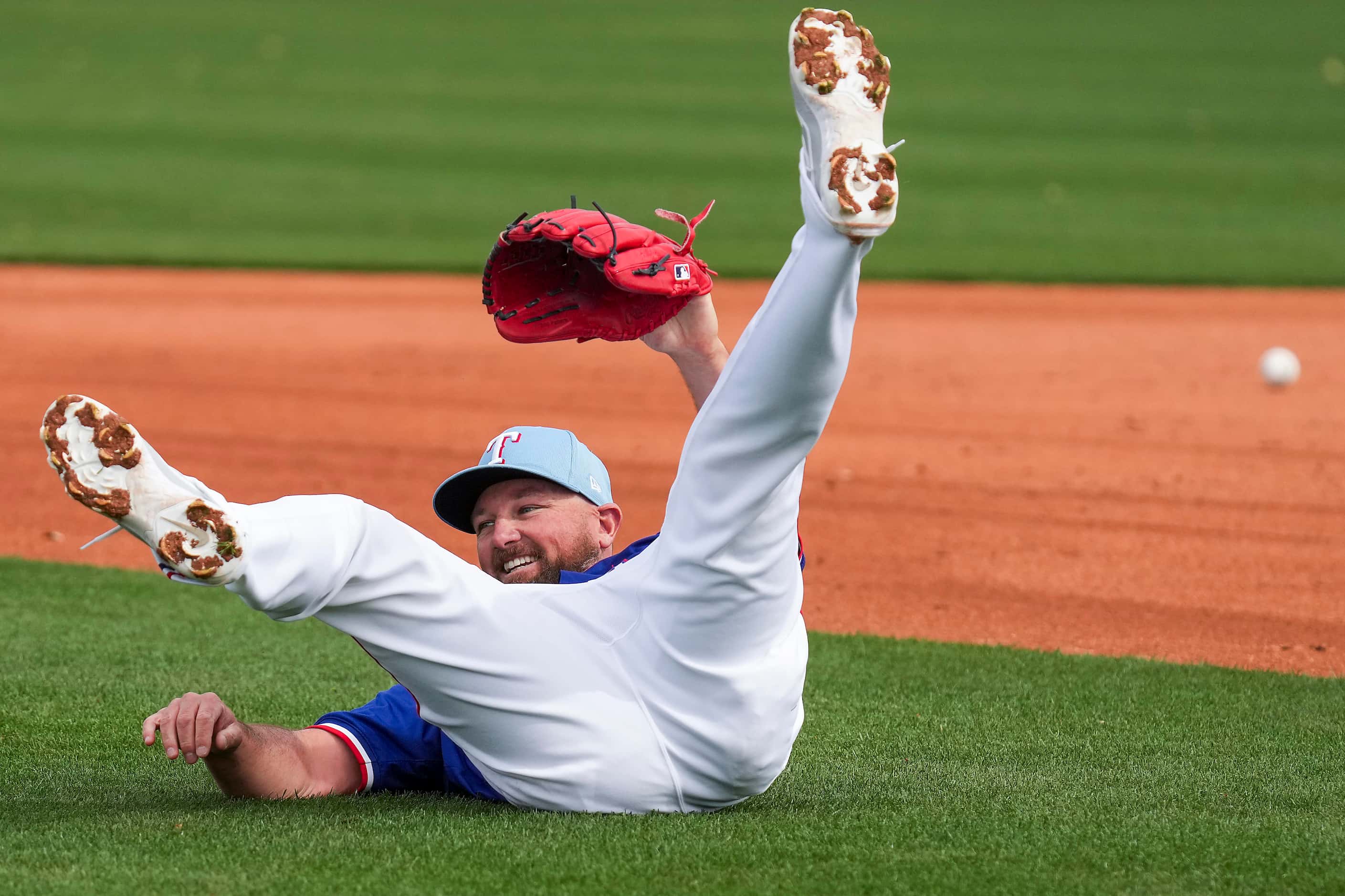 Texas Rangers pitcher Kirby Yates tumbles after diving for a popup in a fielding drill...