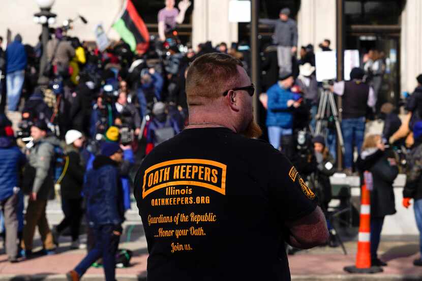 FILE - A man wearing an Oath Keepers shirt stands outside the Kenosha County Courthouse,...