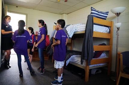 Katie Spellmeyer (left) shows Trinity River Mission students a dorm room during a tour  at...